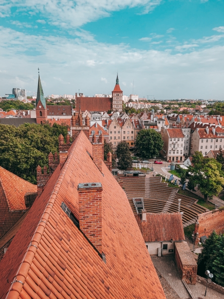 Widok z wieży zamkowej w Olsztynie. Panorama obejmująca dach zamku, amfiteatr, kościół ewangelicki, kamienice Starego Miasta i katedrę w Olsztynie.